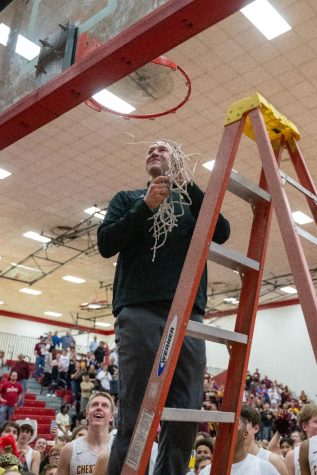 Coach Marc Urban cuts down the net after CHS Boys Basketball win Sectionals.